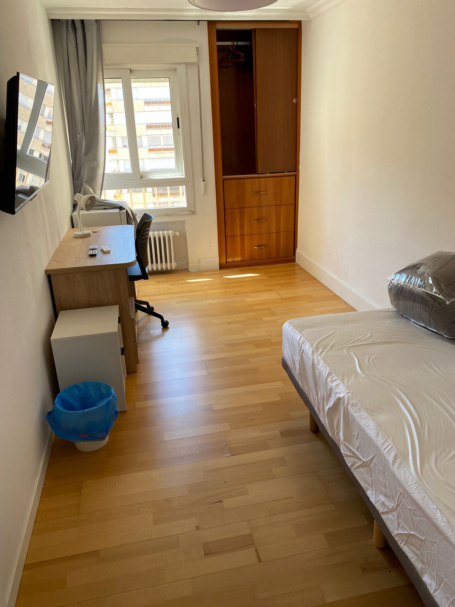 Dormitorio con cama, escritorio y armario después de la limpieza.